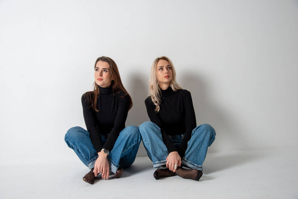 two beautiful girls brunette and blonde posing in studio against gray - Foto, immagini