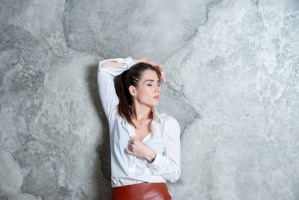 beautiful brunette posing against gray wall - Photo, image
