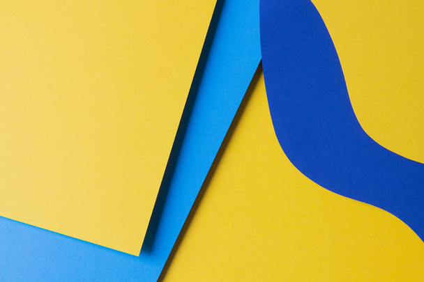 Abstract gekleurde papier textuur achtergrond. Minimale papiersnit stijl compositie met lagen van geometrische vormen en lijnen in gele en blauwe kleuren. Bovenaanzicht. - Foto, afbeelding