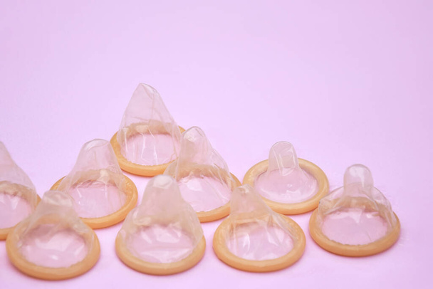 Veel witte pakjes ongeopende condooms op een roze achtergrond. Met behulp van een condoom om de kans op zwangerschap of seksueel overdraagbare ziekten te verminderen, soa. Het concept van veilige seks en reproductieve gezondheid. - Foto, afbeelding