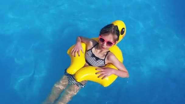 Linda niña con pato de goma se divierte en la piscina - Metraje, vídeo