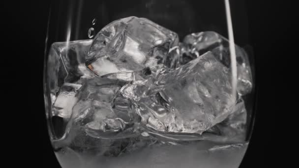 Крупним планом кубики льоду в невеликому склі, лід в прозорому склі, вода в прозорому склі, бризки кубиків водяного льоду повітря піднімаються склянкою повітряних бульбашок. крижаний напій. кубик льоду
 - Кадри, відео