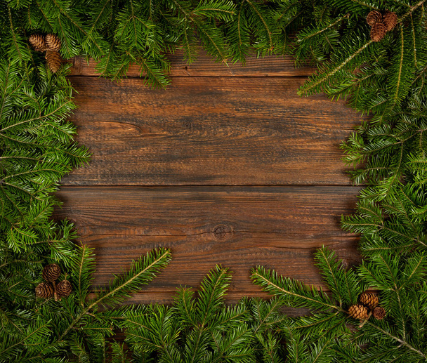 Közelkép határ keret friss zöld lucfenyő vagy fenyő karácsonyfa ágak kúpok felett sötétbarna fa deszkák háttér fénymásoló hely - Fotó, kép