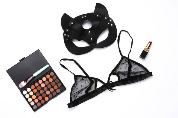 Love, romantic, sexy concept. Leather bdsm sexy cat mask with, lace bra, make-up palette and lipstick on red background. Flat lay - Photo, Image