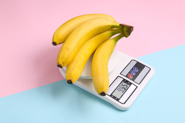 Banán konyhai mérlegen, kék-rózsaszín pasztell háttér - Fotó, kép