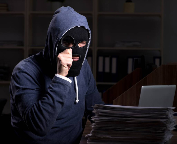 El ladrón masculino en pasamontañas en la oficina por la noche
 - Foto, Imagen