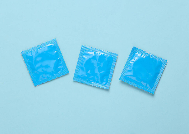 Mavi arka planda üç paket prezervatif. - Fotoğraf, Görsel