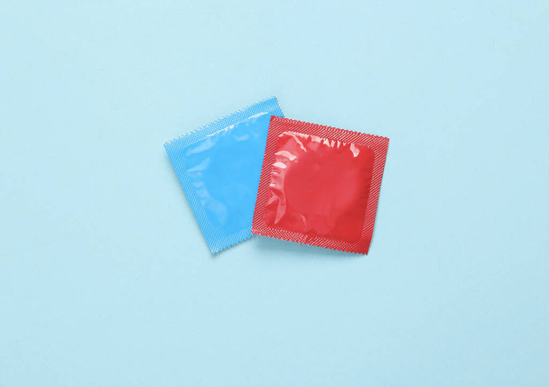 Синьо-червона упаковка презервативів на синьому фоні. Вид зверху
 - Фото, зображення