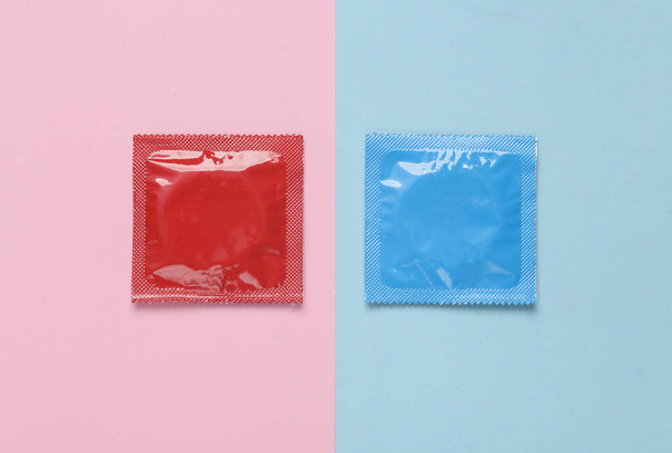 Dos paquetes de condones sobre un fondo pastel de color rosa azulado. Vista superior - Foto, Imagen