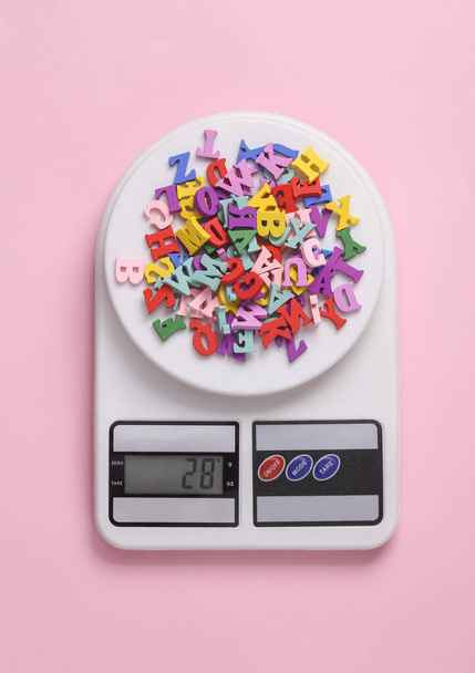 Básculas electrónicas de cocina con muchas letras de colores sobre fondo rosa - Foto, Imagen