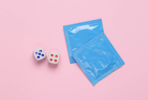 Пачка презервативов с кубиками на розовом фоне - Фото, изображение