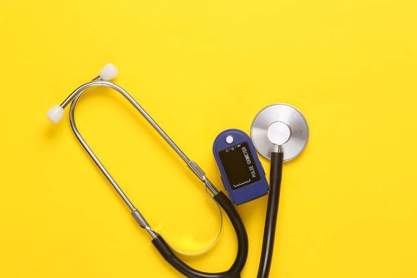 Medizinprodukte zur Diagnose von Gesundheitszuständen. Pulsoximeter, Stethoskop auf gelbem Hintergrund. Ansicht von oben - Foto, Bild