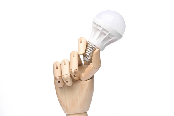 Mão de madeira segurando Lâmpada LED isolada no fundo branco - Foto, Imagem