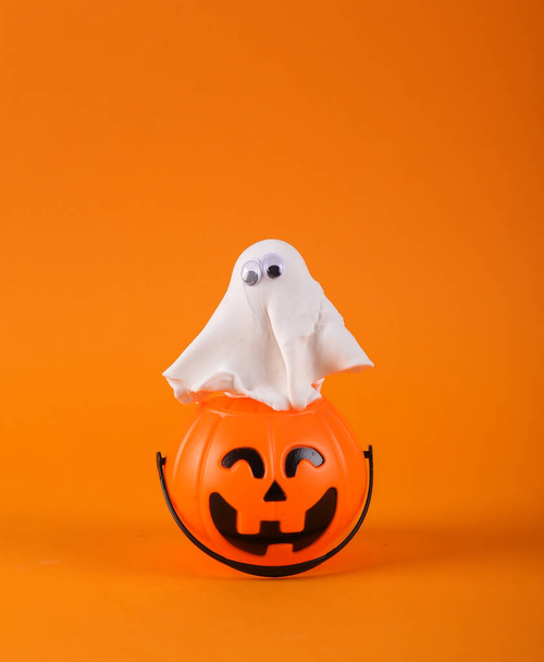 Duch z dyni Jack Candy wiadro na pomarańczowym tle. Sztuczka lub psikus, Halloween martwa natura - Zdjęcie, obraz