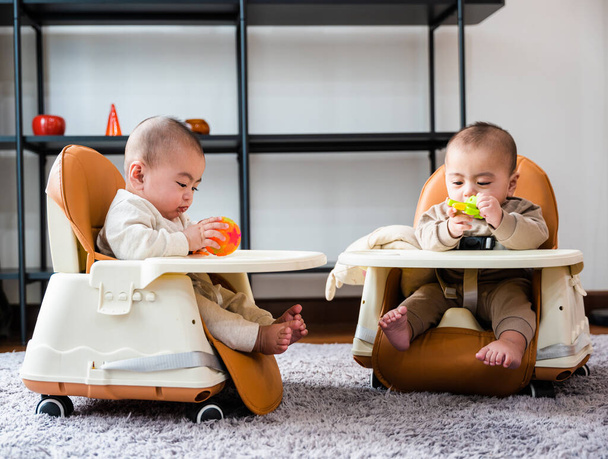 Asian twin babies sitting on safety chair, the chair can use for car seats, Two little baby waiting to eat at home - Foto, Bild