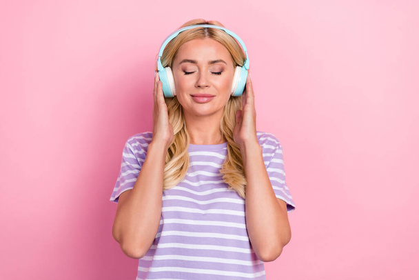 Photo of dreaming closed eyes touch new headphones enjoy her music lover sound relax chill hobby isolated on pastel pink color background. - Foto, Bild
