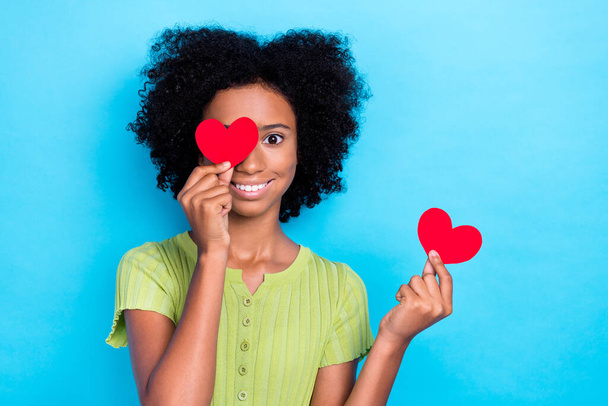 Closeup photo of little positive excited smiling young lady teenager cover eye red paper heart good mood isolated on bright blue color background. - Foto, afbeelding
