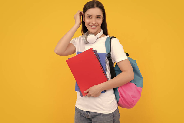 private teacher with copybooks and headphones. back to school. modern education concept. cheerful student hold notebook. girl holding notebook on yellow background. - Valokuva, kuva