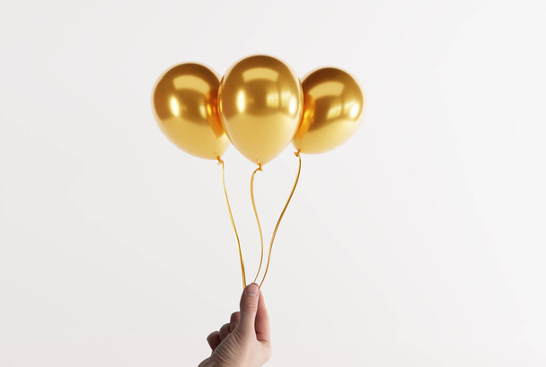 El, arka planda altın balonlar tutuyor. Havayla şişirilmiş balon salınımı kavramı. - Fotoğraf, Görsel