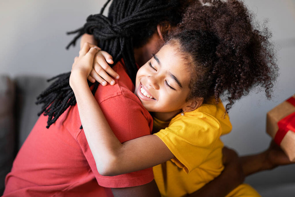 Fathers Day Concept. Happy Preteen Black Girl Embracing Her Dad At Home, Cute Loving Daughter Hugging African American Dad After Giving Present, Greeting With Holidays, Closeup Shot - Фото, изображение