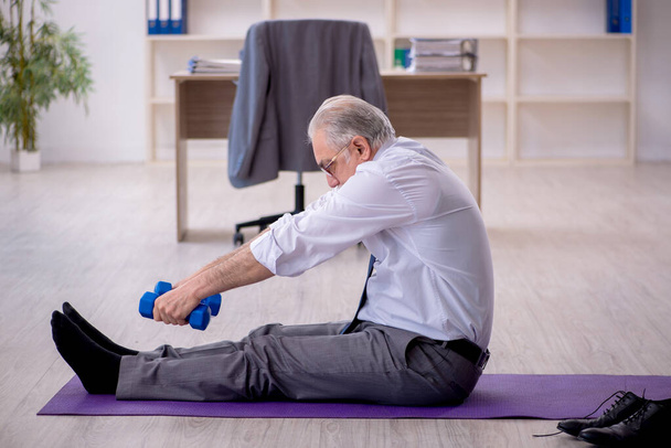 Viejo empleado haciendo ejercicios deportivos durante el descanso - Foto, imagen
