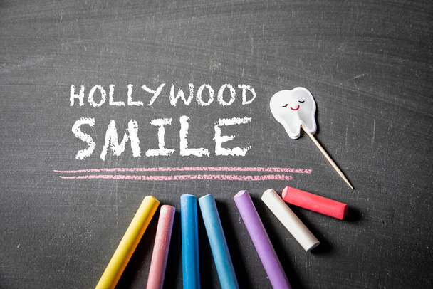 Hollywood lächelt. Text und farbige Stücke Kreide auf einer dunklen Tafel. - Foto, Bild