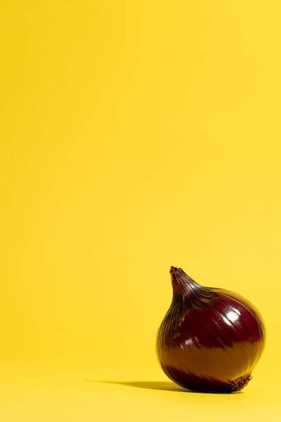 Punainen sipuli keltaisella pohjalla. Minimaalinen kasviskonsepti - Valokuva, kuva