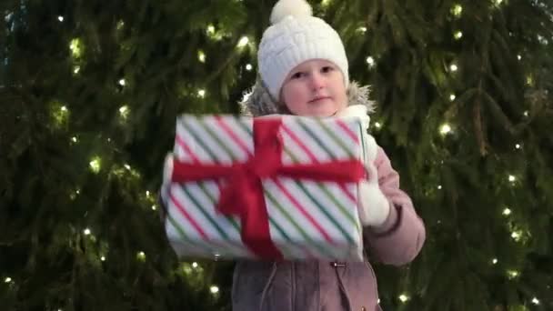 Gelukkig klein meisje met kerstdoos cadeau in de winter buiten op kerstavond. Kerstcadeautjes Vakantie kindertijd concept - Video