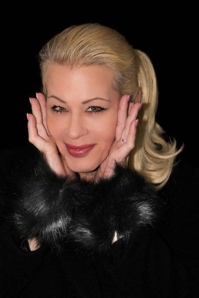 Jolie femme blonde portant un manteau en cachemire noir sur un fond noir - Photo, image