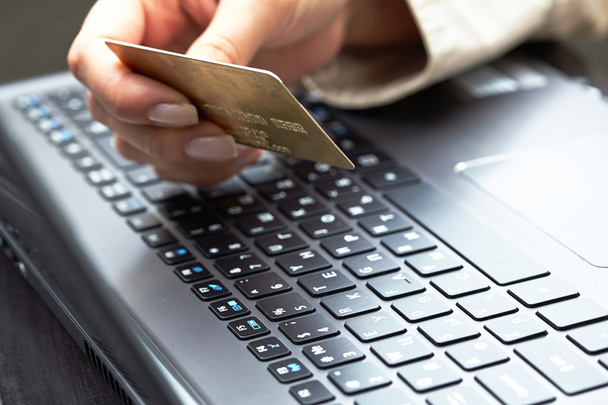 Femme tenant une carte de crédit sur un ordinateur portable
 - Photo, image