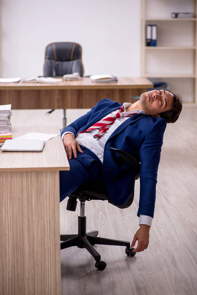 Молодой бизнесмен и слишком много работы в офисе - Фото, изображение