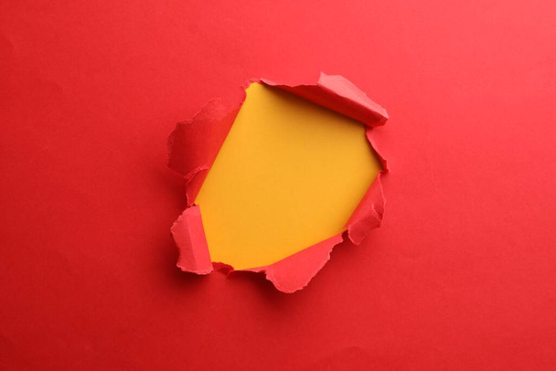 Hole in red paper on yellow background - Photo, image