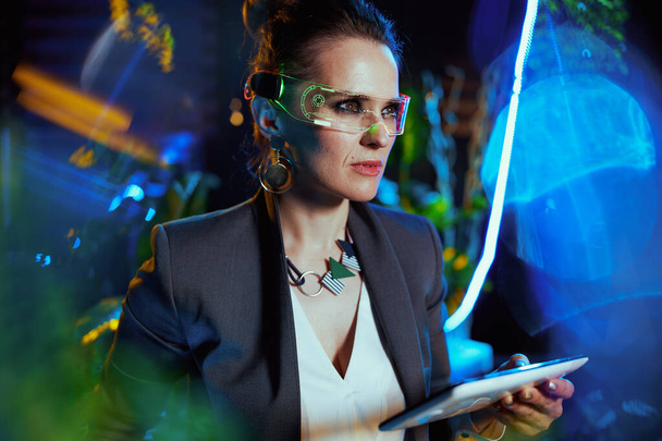 stylish 40 years old business woman with futuristic goggles and tablet PC in metaverse. - Foto, imagen