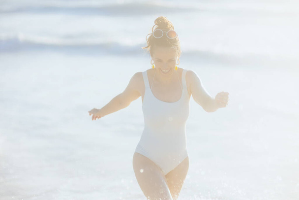 smiling elegant female in white swimwear at the beach having fun time. - Valokuva, kuva