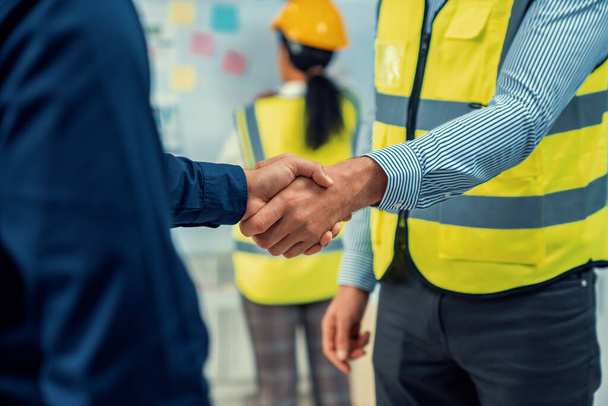 After concluding the meeting, competent investor shakes hands with engineer. Concept of the agreement between engineers and investors. - Foto, afbeelding