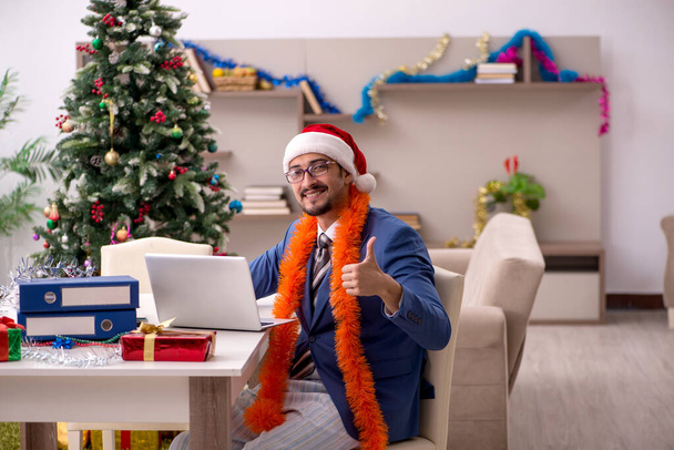 Young male employee working from home at Christmas eve - Photo, Image