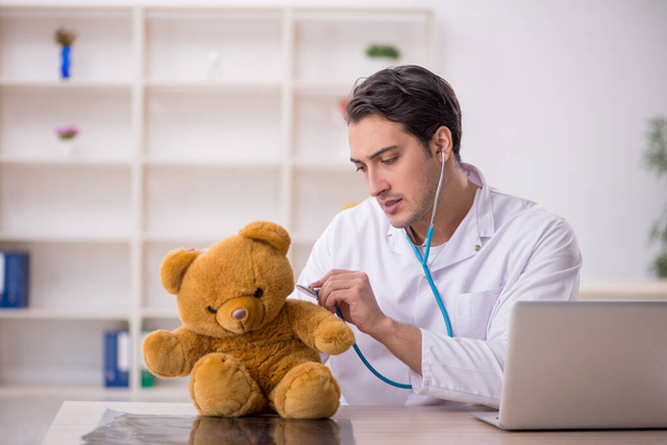 Молодий лікар тримає іграшкового ведмедя
 - Фото, зображення