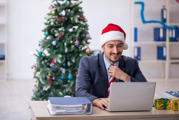 Mladý zaměstnanec slaví Vánoce v kanceláři - Fotografie, Obrázek