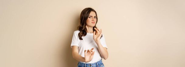 Young woman cringe, shaking hands to decline, reject disgusting bad offer, standing over beige background. Copy space - Photo, Image
