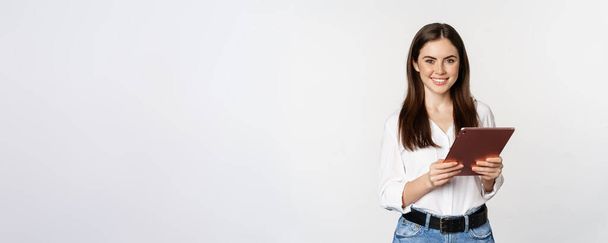 Πορτρέτο της χαμογελώντας εταιρική γυναίκα κοιτάζοντας ψηφιακή ταμπλέτα, εργασίας, στέκεται πάνω από το λευκό φόντο. - Φωτογραφία, εικόνα