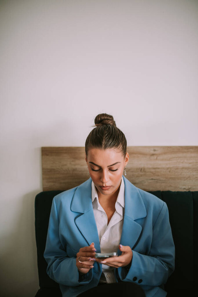 Красивая деловая женщина смотрит на свой телефон, сидя в кафе - Фото, изображение