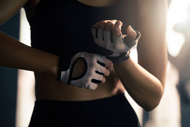 女性はジムで運動のためのフィットネス手袋を置く. - 写真・画像