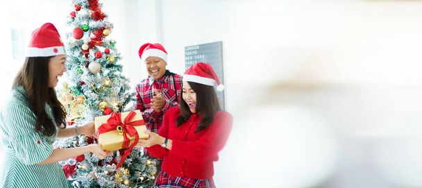 Happy Asian people enjoy decorating a Christmas tree with a fantasy Christmas balls and presents together. Happy people preparing their residency or home for celebrating new year and Christmas party. - Foto, Imagen