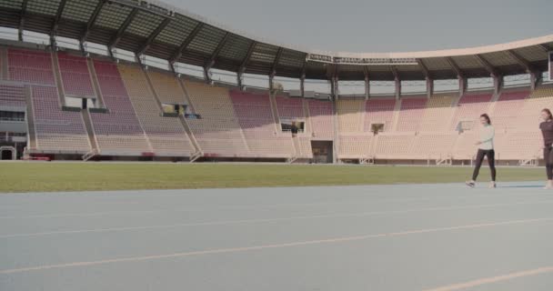 Three young people preparing to compete on the running track at an empty stadium - Footage, Video