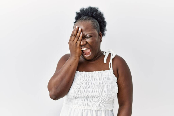 Mujer africana joven de pie sobre fondo blanco aislado bostezando cansado cubriendo media cara, ojos y boca con la mano. cara duele en el dolor.  - Foto, Imagen