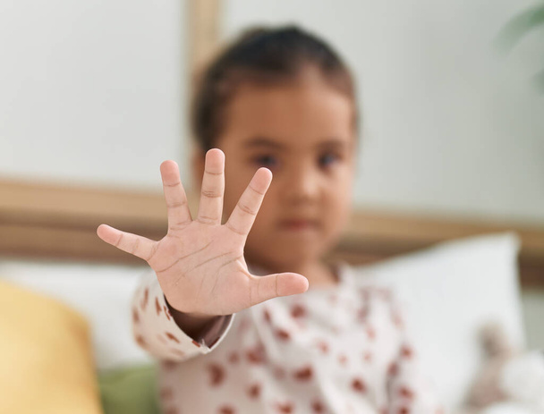 Чарівна іспаномовна дівчина робить стоп жест рукою в спальні
 - Фото, зображення