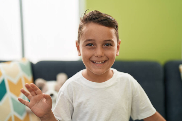Adorable bambin hispanique souriant confiant disant bonjour avec la main à la maison - Photo, image
