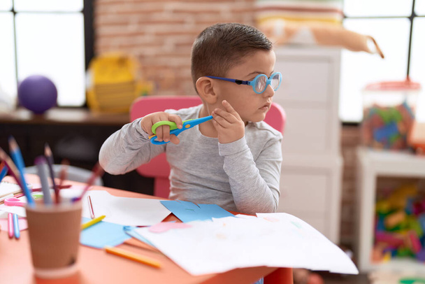Adorable hispanic toddler student cutting paper at classroom - Photo, Image