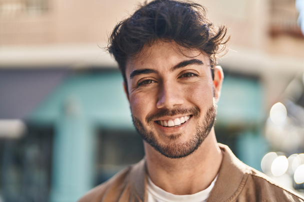 Mladý hispánec se usmívá sebevědomě stojí na ulici - Fotografie, Obrázek