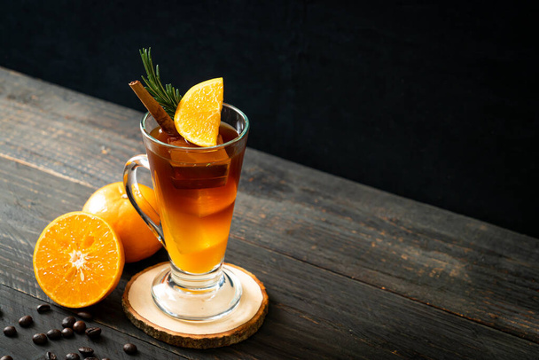 A glass of iced americano black coffee and layer of orange and lemon juice decorated with rosemary and cinnamon - Foto, Imagen
